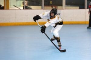 Young hockey player in motion, skillfully maneuvering on a blue rink during a roller hockey game.