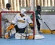 A goalie in a white Tigers jersey defends the net while players compete in a roller hockey game.