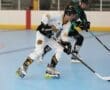 Two players compete in a roller hockey match, showcasing speed and agility on a blue rink surface.
