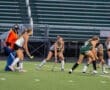 Field hockey players compete during an intense match, focusing on the ball and their positions on the field.