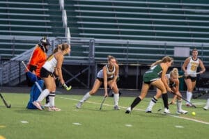 Field hockey players compete during an intense match, focusing on the ball and their positions on the field.