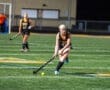Field hockey players in action during a night game on a synthetic turf field, focusing on teamwork and skill.