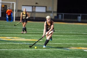 Field hockey players in action during a night game on a synthetic turf field, focusing on teamwork and skill.