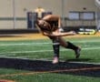 Field hockey player executes a powerful shot on goal under evening lights, showcasing skill and athleticism.