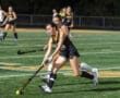 Female field hockey players in action during a night game, showcasing teamwork and athleticism on a vibrant turf field.