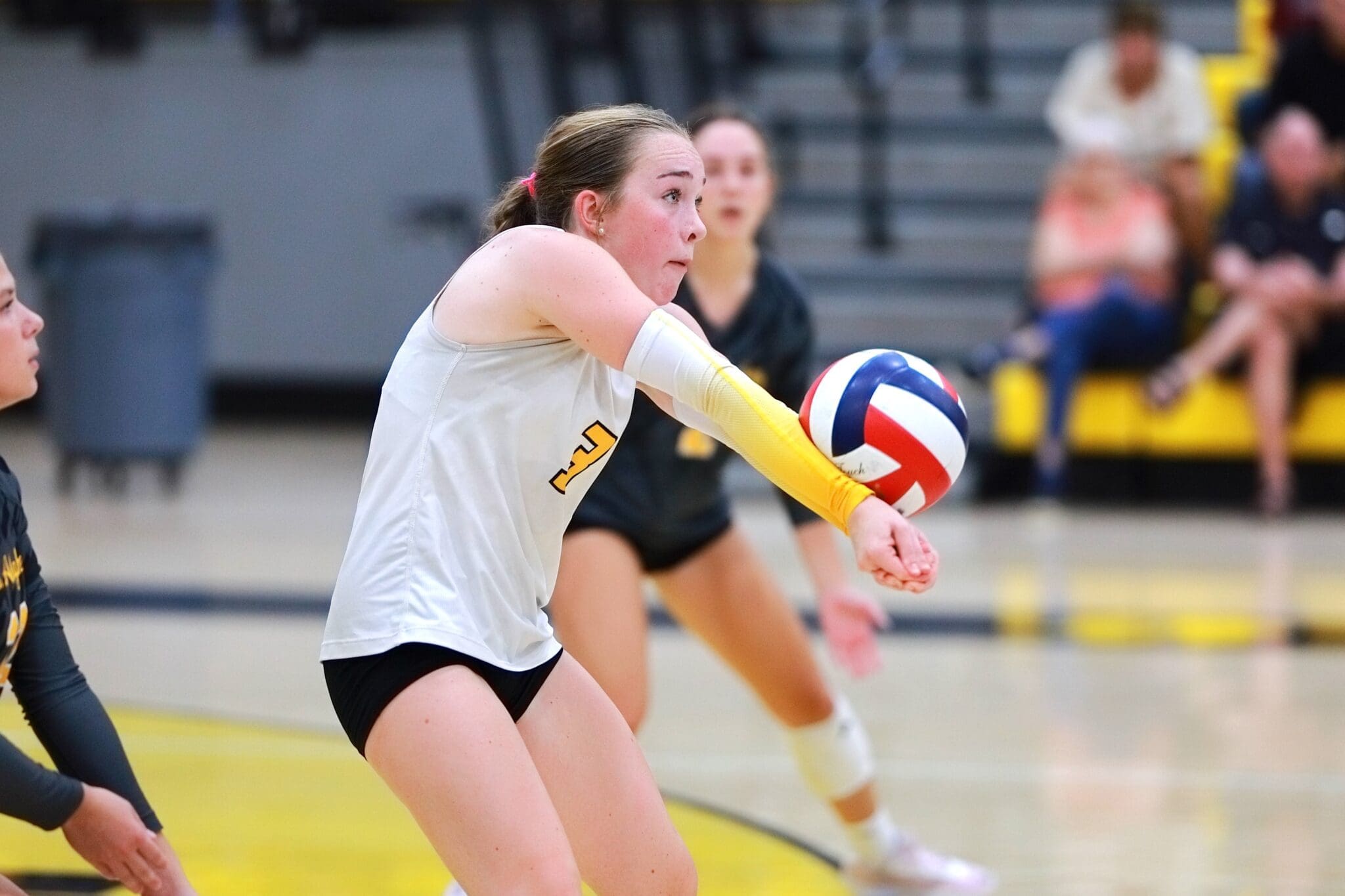 Player in a volleyball game prepares to receive the ball, showcasing athleticism and teamwork in action.