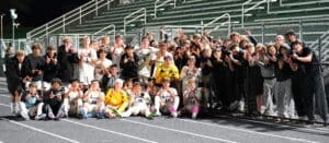 North Allegheny soccer team poses together in celebration, showcasing teamwork and school spirit under stadium lights.