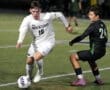 North Allegheny soccer player dribbles the ball past an opponent during an intense night match on the field.