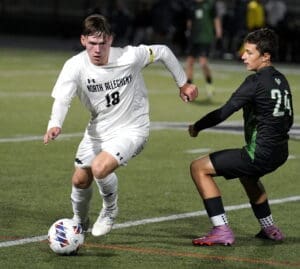 North Allegheny soccer player dribbles the ball past an opponent during an intense night match on the field.