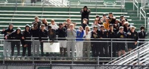 Group of students posing with playful expressions in a stadium, showcasing team spirit and camaraderie.