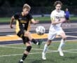 Two high school soccer players compete for the ball on a field, showcasing skill and athleticism during the match.