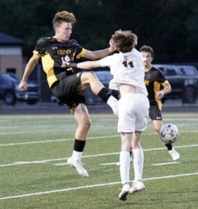 High school soccer players clash during a match, highlighting competitive gameplay and athleticism on the field.