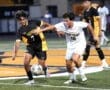 Two high school soccer players compete for the ball during a match, showcasing athleticism and teamwork on the field.