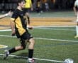 Varsity soccer player dribbles the ball on a field during a night game, showcasing athleticism and team spirit.