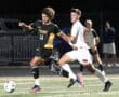 High school soccer players sprint for the ball in a dynamic game under stadium lights.