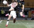 Two soccer players compete for the ball during a nighttime match, showcasing intense athleticism and teamwork.