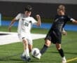 Two soccer players contest the ball during a night game, showcasing athleticism and competition on the field.