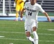 North Allegheny soccer player #14 dribbles the ball during a night game on a well-lit field.
