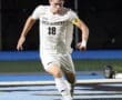 North Allegheny soccer player in action, wearing jersey number 18, dribbling the ball on the field during a night game.