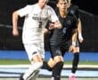 North Allegheny soccer player sprinting with the ball while being pursued by an opponent on a lit field.