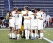 A youth soccer team huddles together for motivation before a game on the field. Team spirit and unity are highlighted.
