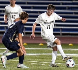 North Allegheny soccer players compete on the field during a night game, showcasing athleticism and teamwork.