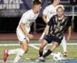 Two high school soccer players in action: one in a white uniform from North Allegheny and another in blue from Butler.
