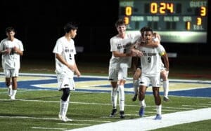 North Allegheny soccer team celebrates a goal under stadium lights, with 24 seconds left in the game. Scoreboard shows 0-3.