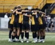 High school soccer team huddling together in team unity before a match on the field. Team spirit and preparation.