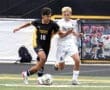 High school soccer players compete for the ball during a match, showcasing athleticism and teamwork on the field.