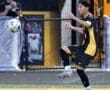 High school soccer player skillfully controls a flying ball during a match on the field, showcasing athletic ability.