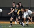 High school soccer players compete for the ball during a nighttime match, showcasing athleticism and teamwork.