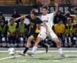 High school soccer players in action, battling for the ball under rain, showcasing athleticism and teamwork.
