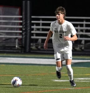 North Allegheny soccer player in action on the field, dribbling the ball under stadium lights during a match.