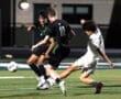 High school soccer players battling for the ball on a night game, showcasing dynamic action and teamwork.