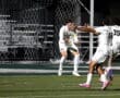 Soccer players celebrate a goal under stadium lights, showcasing team spirit during an exciting match.