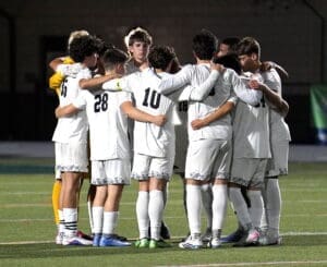 Soccer team huddling together for strategy before a match, showcasing teamwork and unity on the field.