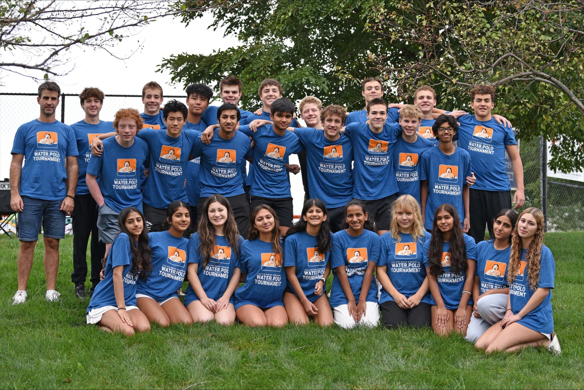 Group photo of water polo team wearing blue shirts at a tournament, showcasing camaraderie and teamwork.