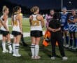 Field hockey players gather for a pre-game meeting under stadium lights, showcasing teamwork and sportsmanship.