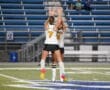 Two female soccer players jump in celebration on the field, wearing uniforms with the numbers 7 and 4.