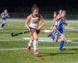 Field hockey players compete at night, showcasing skill and teamwork on the turf during an intense match.