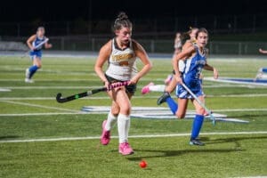 Field hockey players compete at night, showcasing skill and teamwork on the turf during an intense match.