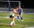 Field hockey players in action during a night game, showcasing teamwork and athleticism on the turf.