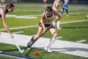 Field hockey players compete for the ball during a night match, showcasing teamwork and athleticism on the turf.