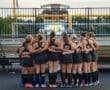 A group of young female athletes huddle together in preparation for their field hockey match. Team spirit captured.
