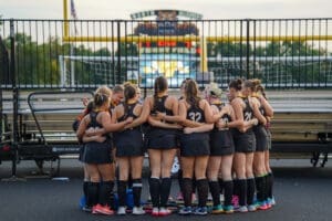 A group of young female athletes huddle together in preparation for their field hockey match. Team spirit captured.