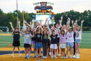 Cheerleading team of girls celebrating at Wright Field, North Allegheny, with hands raised in excitement.