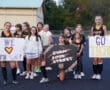 Cheerleaders and youth supporters holding signs at a sports event, promoting positivity and team spirit for the Tigers.