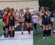 Field hockey team celebrates as players run through a cheering tunnel, showcasing teamwork and school spirit during a game.
