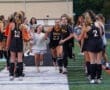 Team celebration as players run through a spirit line of teammates, showcasing joy and camaraderie at a field hockey event.